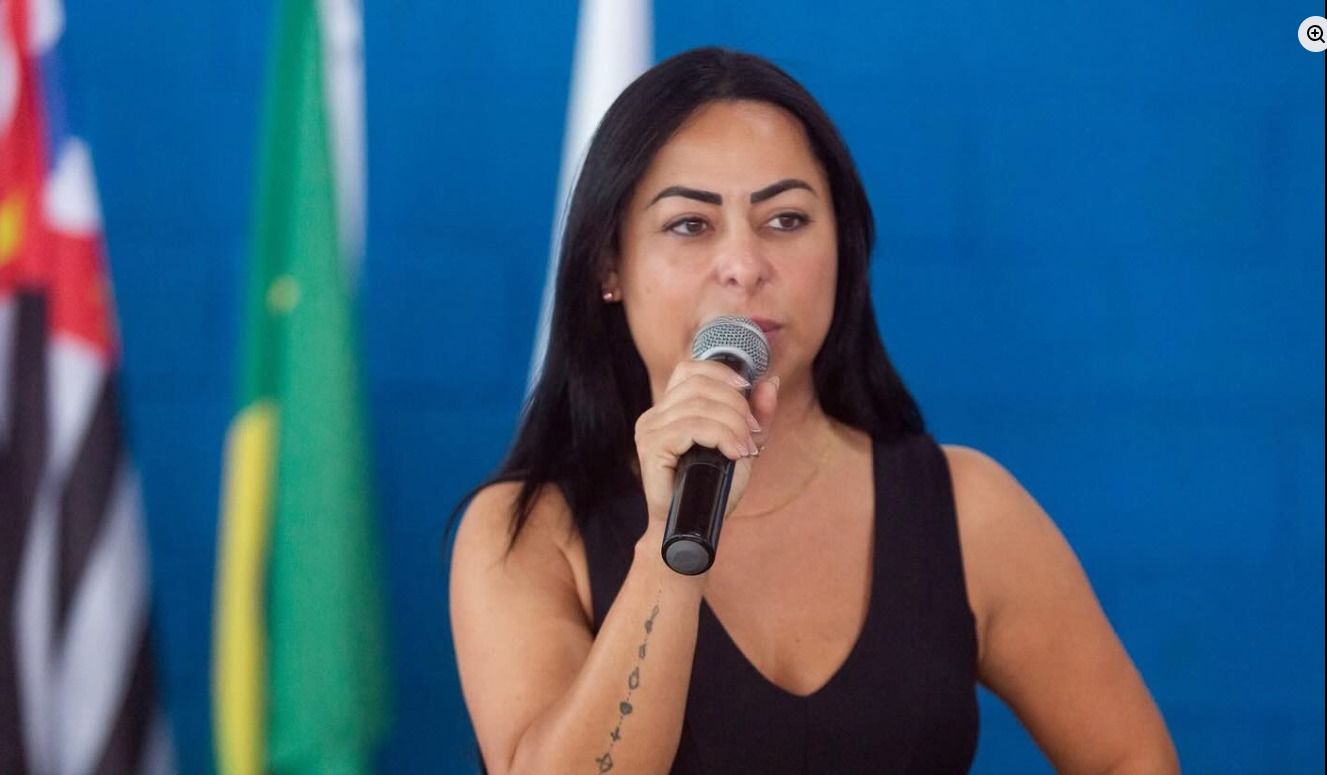 Mirelle Trevisan fala ao microfone durante um encontro público.